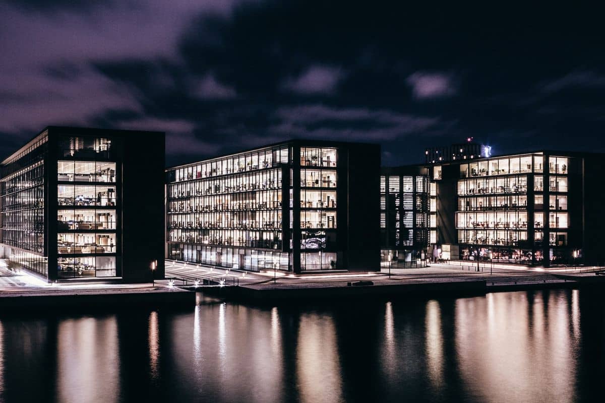 Mehrere Bürogebäude in der Dunkelheit vor einem Gewässer