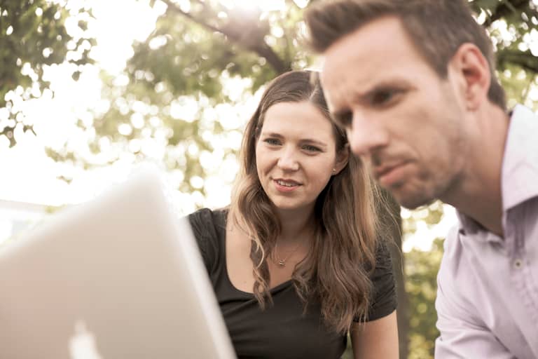 Eine Frau und ein Mann schauen auf den Bildschirm eines Laptops